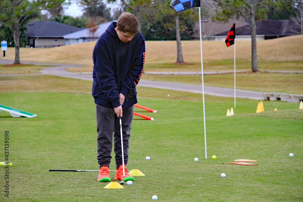 Obraz premium Teen applies methods to learn golf putting