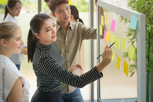 Business people meeting at office and use post it notes to share idea together. Post it note on glass wall. Brainstorming ,workshop and teamwork concept.
