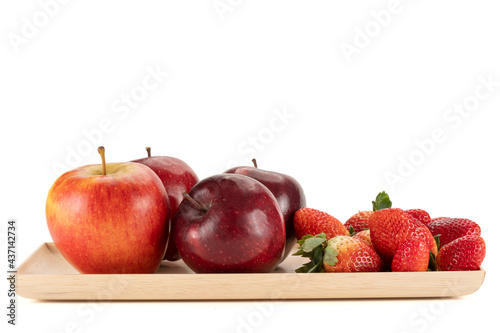 Fresh apples and strawberries on a wooden plate.