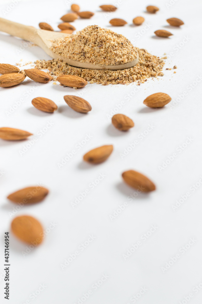 Pieces of floating almonds on white background and almond flour in wooden spoon. Healthy concept Pieces of floating almonds on white background and almond flour in wooden spoon. Healthy concept