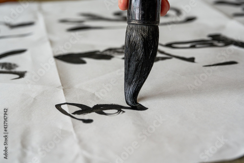 A calligrapher is writing calligraphy characters with a large brush, a close-up of the brush. Translation: The heights are too cold