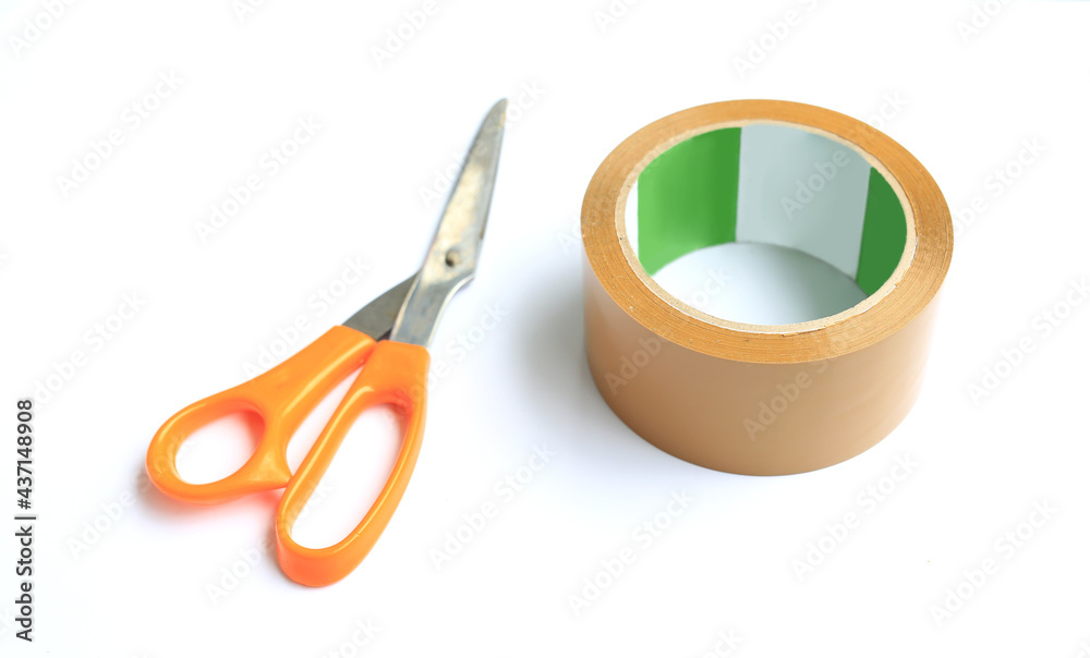 Coil adhesive tape and scissors isolated over white background. Universal packaging equipment. Selective focus Coil adhesive tape and scissors isolated over white background. Universal packaging equipment. Selective focus