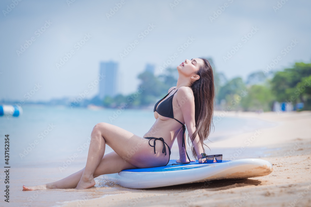 Portrait sexy beautiful Asian model wearing bikini swimming suite and sun glasses posing happy on beach with surfboard is water sport game and hobby leisure in summer holiday lifestyle. 