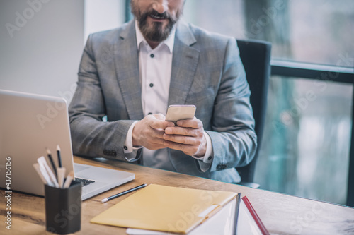 Business man with smartphone in hands sitting in office