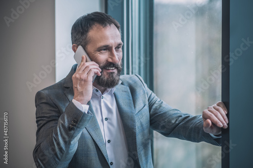 Successful man in suit talking positively on smartphone