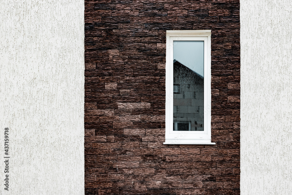 Facade stucco. Wall of house with self-made plastered facade and dark decorative torn brick.