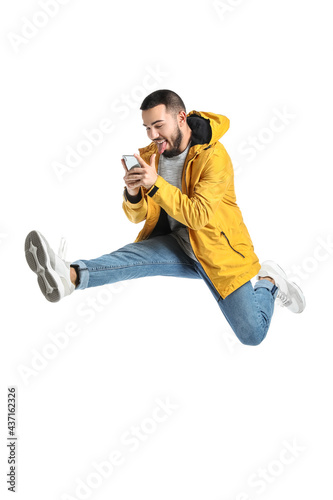Jumping young man with mobi...