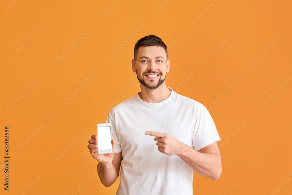Young man pointing at mobile phone on color background Young man pointing at mobile phone on color background