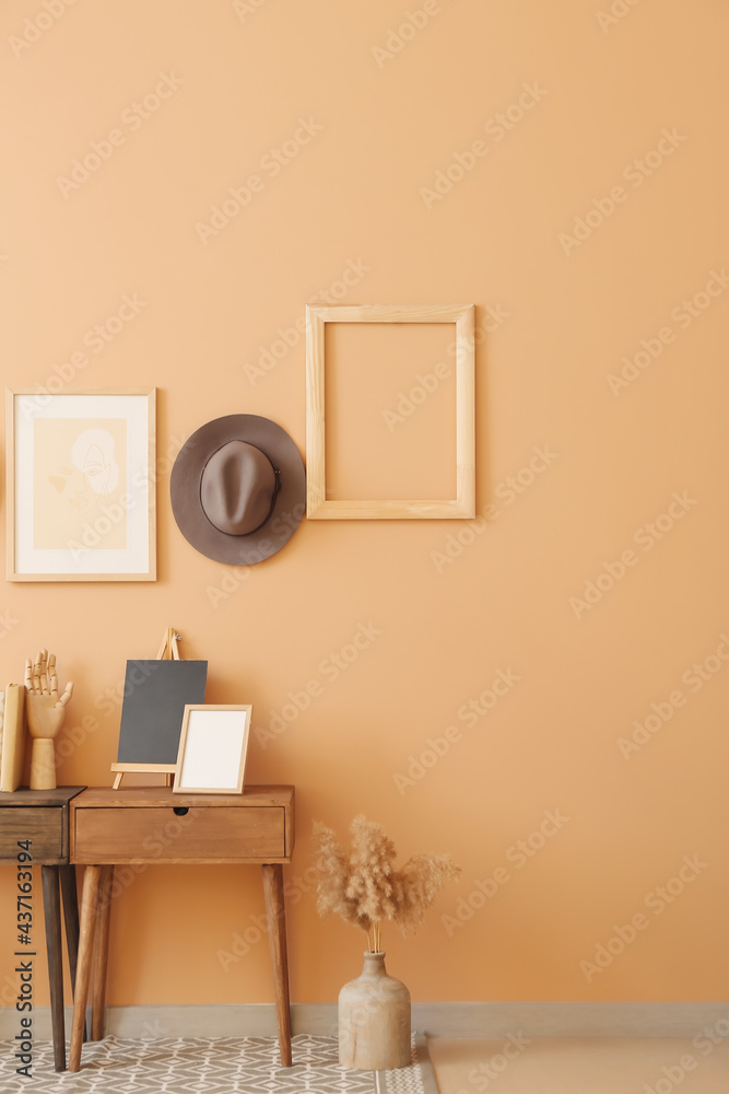 Interior of stylish room with table and hat hanging on color wall Interior of stylish room with table and hat hanging on color wall