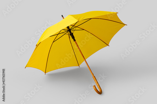 Stylish yellow umbrella on light background