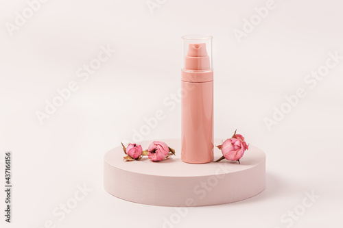 Aroma beauty cream container with essential oil flower of rose on round podium. Cosmetic product, pink pastel colored photo