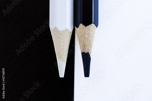 Black and white pencils on a black-red background closeup