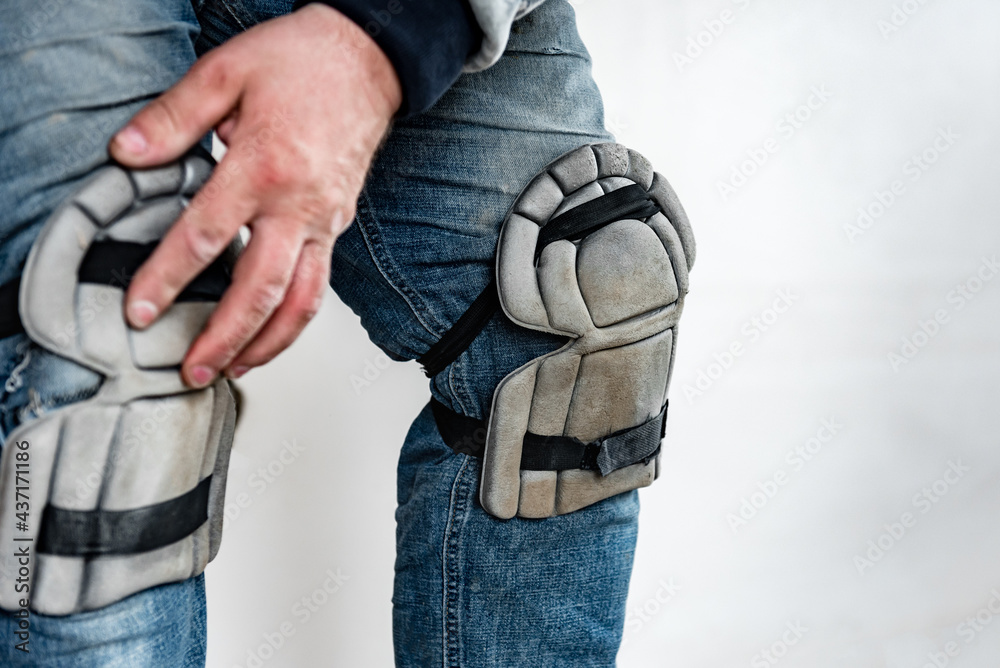 Builder wearing knee protection pads to work in a construction. Safety at work.