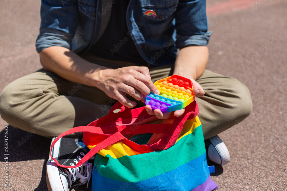 Man with rainbow pop it toy, lgbt bag, pride month