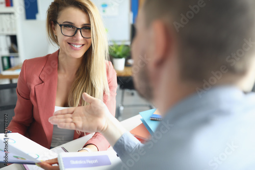 Young man and woman are discussing with charts in their hands photo
