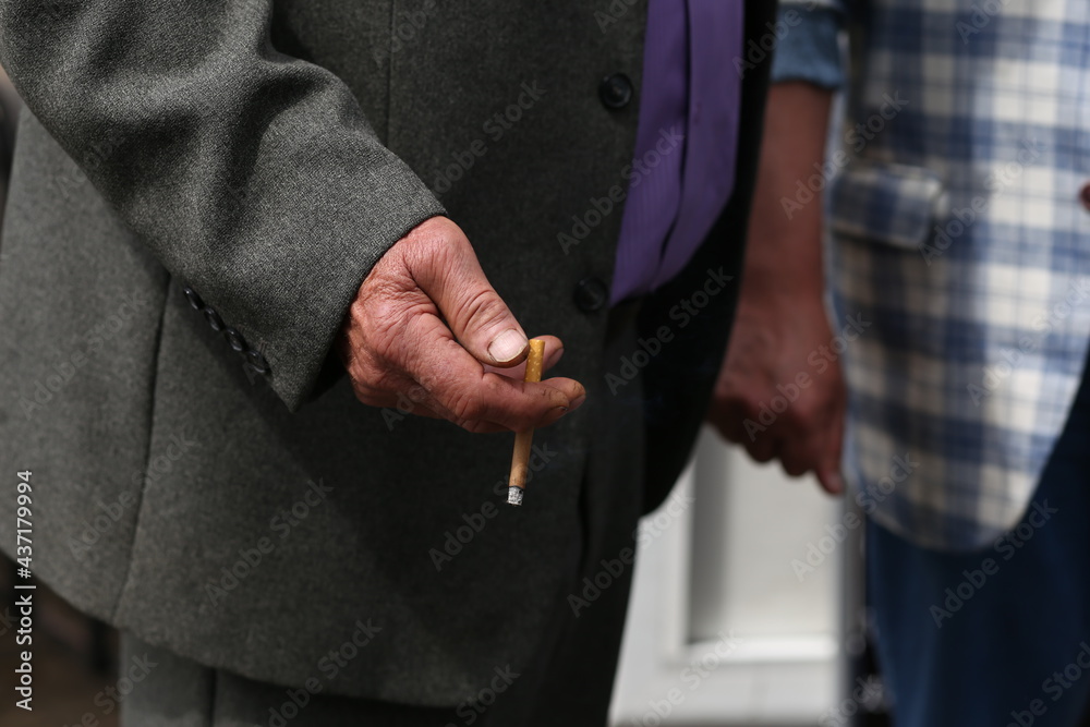 a cigarette in the hand of an elderly man