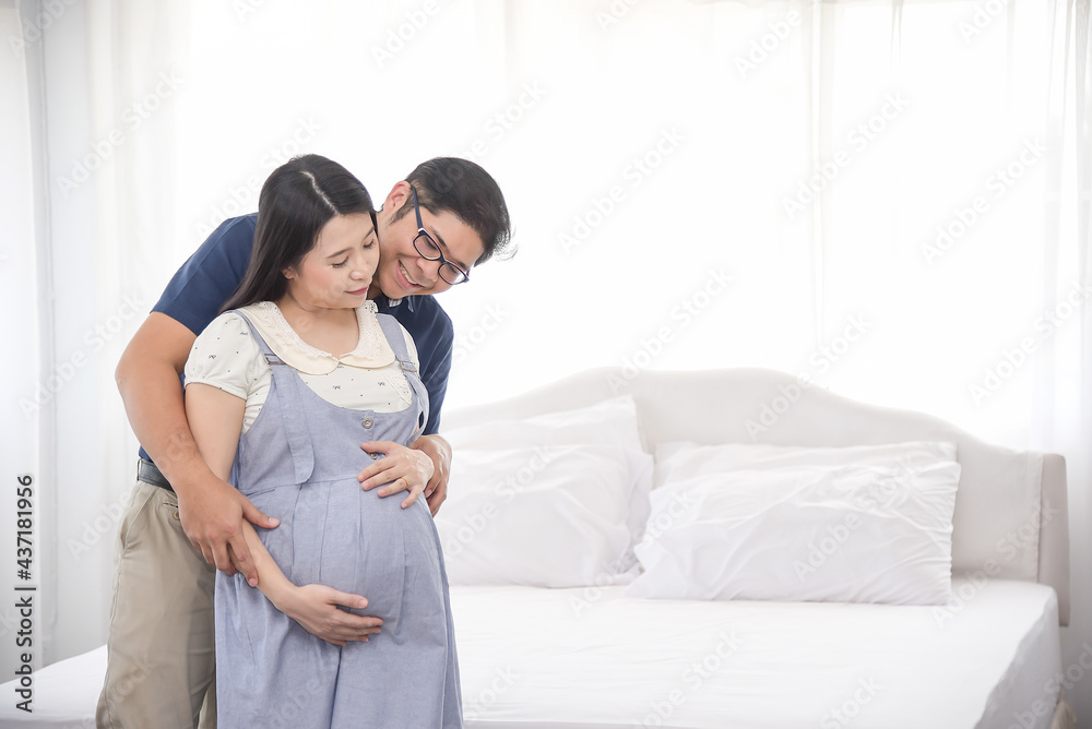 Asian couple sitting and embracing wife 8 months tummy. Family waiting for newborn baby. Asian couple sitting and embracing wife 8 months tummy. Family waiting for newborn baby.