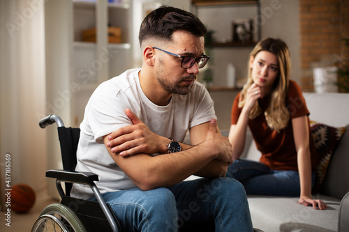 Young sad man in a wheelchair. Girlfriend comforting her sad boyfriend.