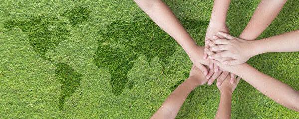 World environment day with global community teamwork, CSR and ESG environmental energy saving collaboration of young children hands stack together on green background for sustainable development goal
