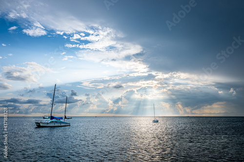 2 sailing boats anchored in the ocean waiting for the sunrise to go out to sea.
