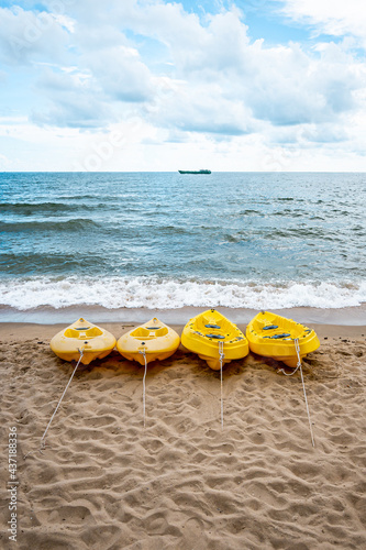 Kayaks on the beach leading out to the ocean. Waves crashing on the shore with blue water.