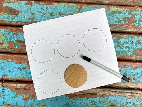 A square sheet of cardboard with drawn circles on the template.