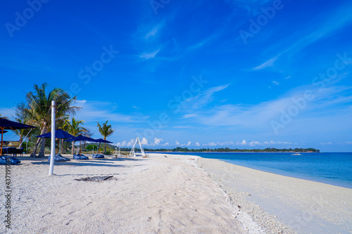Tropical sea with white sand beaches, blue sea, blue sky, green trees and sun lounge. Gili Trawangan, Indonesia