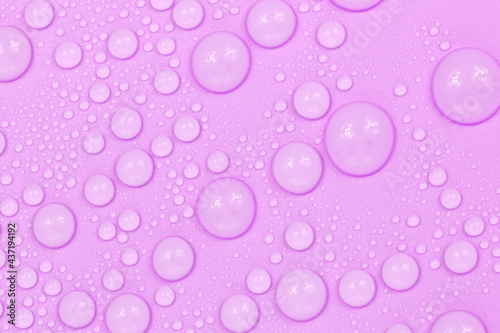Water drops on purple background texture. Backdrop glass covered with drops of water. violet bubbles in water
