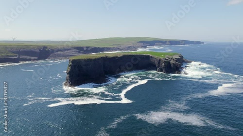 Aerial view of Illaunonearaun islet with Kilkee cliffs and wind turbines in the background. photo