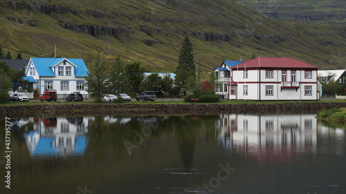 Colorful traditional buildings and houses in the green nature on the picturesque fjord, reflect in the sea water, Seydisfjordur, Iceland