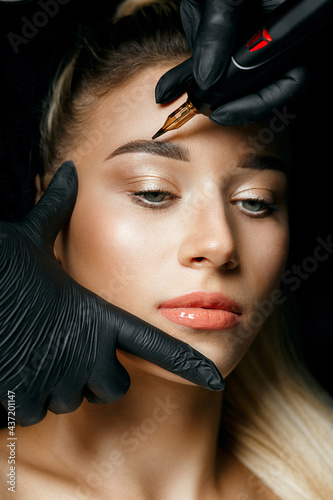 Cosmetician in gloves doing permanent makeup photo