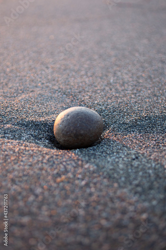 round stone on the sand on the beach by the sea