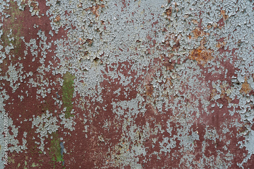 Fragment of an old steel wall. Remnants of layers of brown primer and gray paint have remained on the surface. There are rusted areas. Background. Texture.