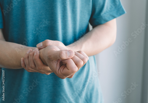 male arms holding his painful wrist caused by prolonged work on the computer, laptop,neurological disease concept. Numbness of the hand