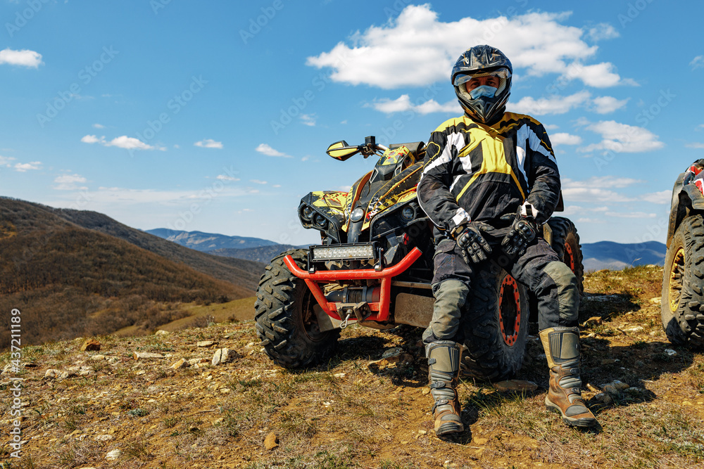 Man in helmet sitting on ATV quad bike in mountains Man in helmet sitting on ATV quad bike in mountains