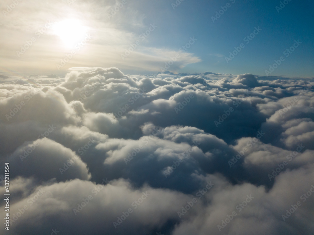 Aerial high flight above the clouds at sunrise.