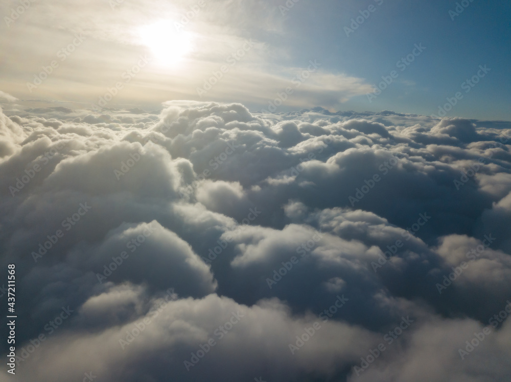 Aerial high flight above the clouds at sunrise.