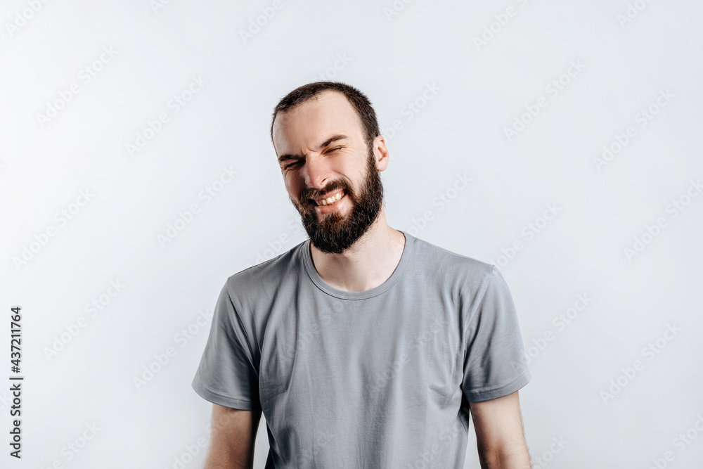 Handsome young brunette man frowning and closing eyes, angry on white background with space for advertising mock up