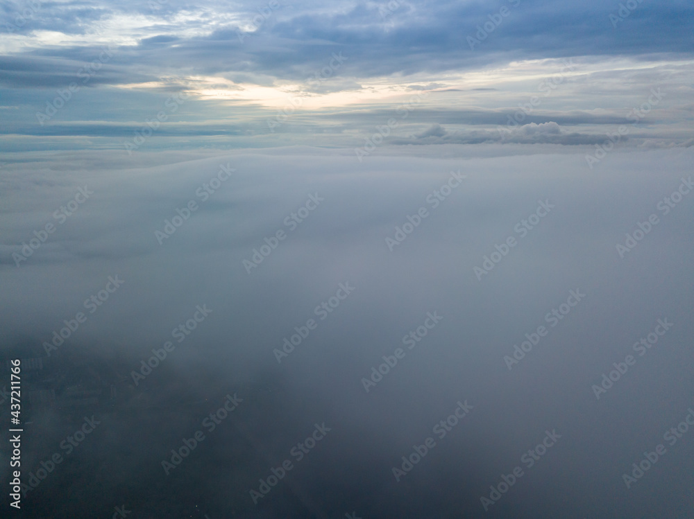 Aerial high flight above the clouds. The rays of the rising sun break through the clouds.