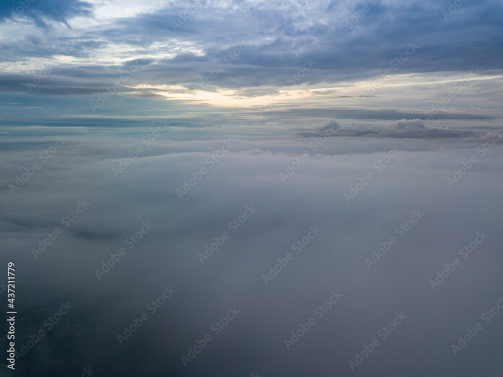 Fototapeta premium Aerial high flight above the clouds. The rays of the rising sun break through the clouds.