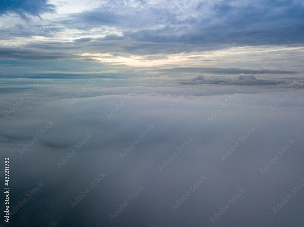 Aerial high flight above the clouds. The rays of the rising sun break through the clouds.