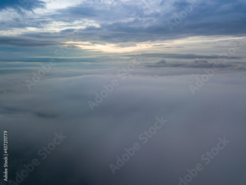 Aerial high flight above the clouds. The rays of the rising sun break through the clouds. © Sergey