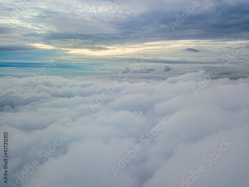 Aerial high flight above the clouds. The rays of the rising sun break through the clouds.