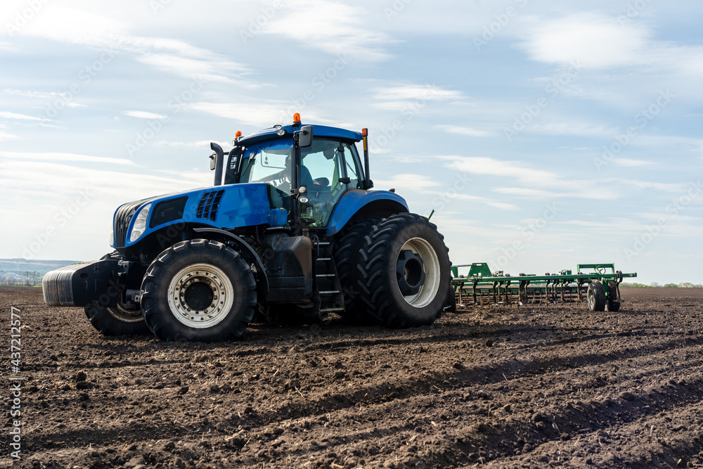 A tractor with seedbed cultivator ploughs field on morning. A tractor with seedbed cultivator ploughs field on morning.
