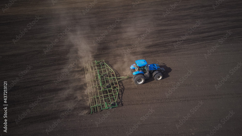 Photo from the drone of a tractor with seedbed cultivator ploughs field
