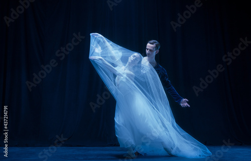 Graceful balerina in image of ghost bride with patner in art ballet performance isolated over dark background. photo