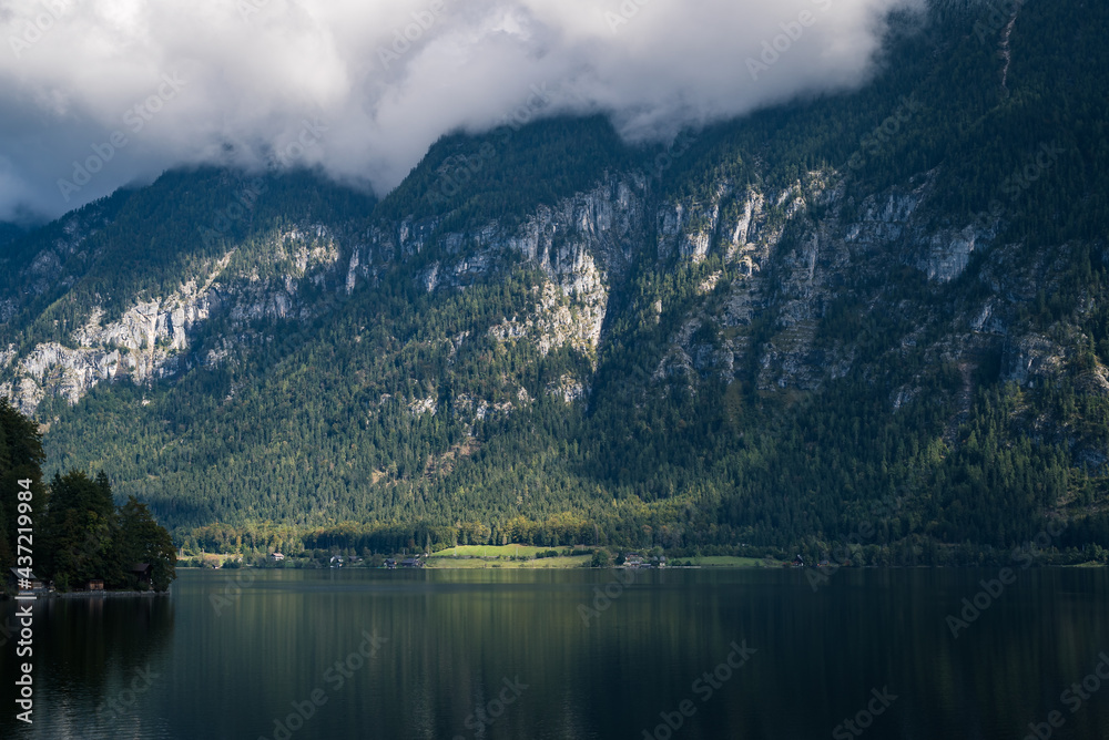 Panoramic view overlooking the beautiful lake of Hallstatter see with tiny houses and a landscape of mountains in the background.
