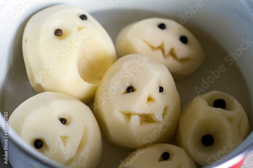 peeled potatoes in a saucepan with cut-out faces