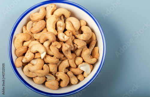 Cashew fruit in white bowl on the blue background. Top view.