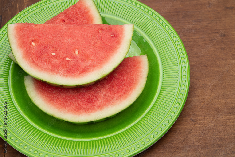Fresh slices of watermelon on a green plate and old farm table Fresh slices of watermelon on a green plate and old farm table